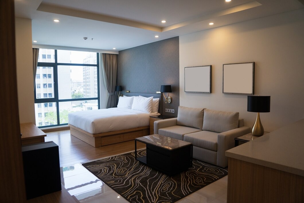A modern hotel room featuring a bed, a couch, and a large window with natural light streaming in